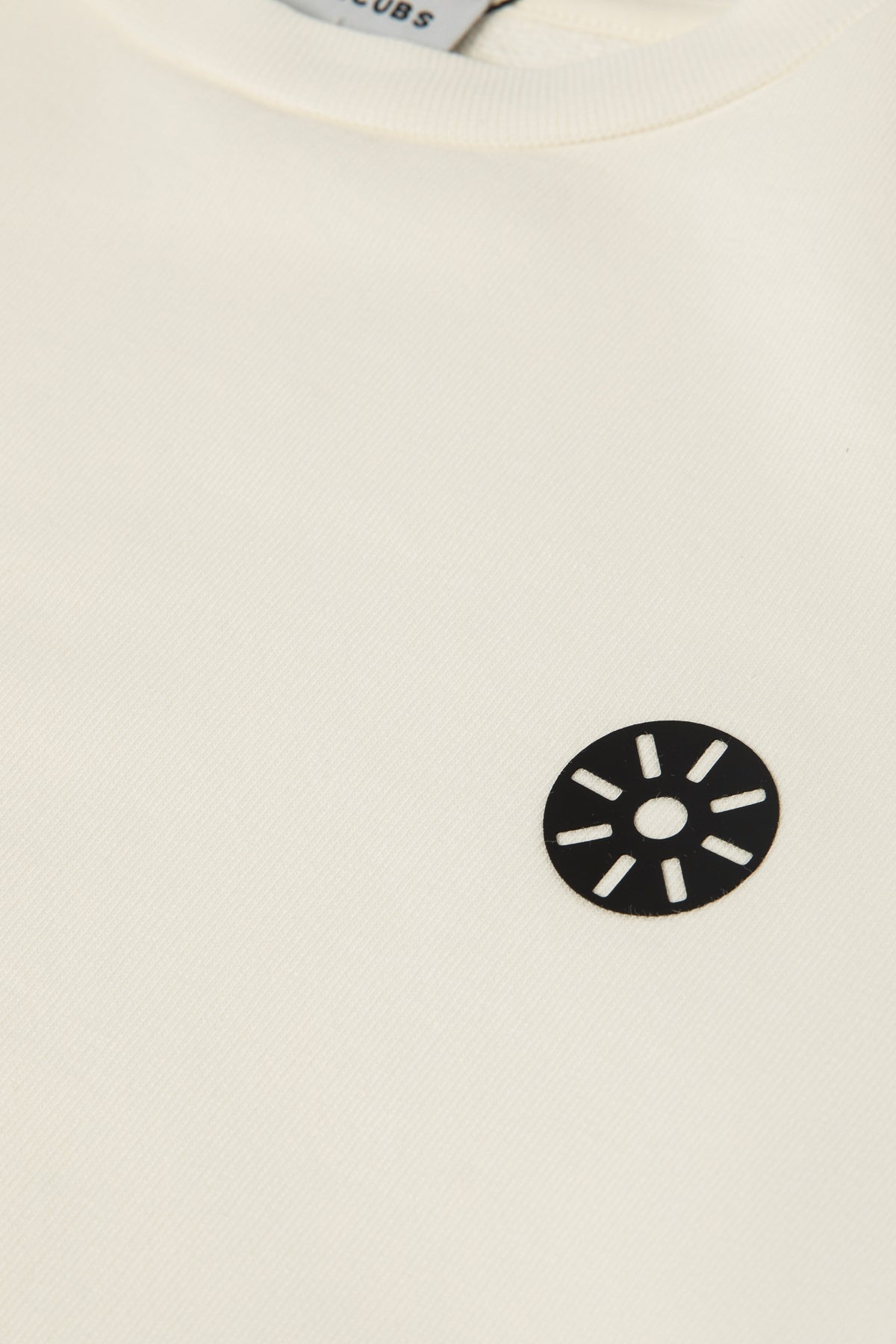 Close-up of Goldencubs white cotton boys sweatshirt showing soft ribbed neckline and signature black circular logo patch — premium cotton quality detail.