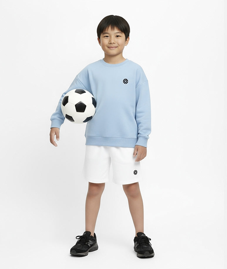 Front view of boy wearing Goldencubs baby blue cotton sweatshirt and white shorts while holding a soccer ball — casual and sporty kids outfit.