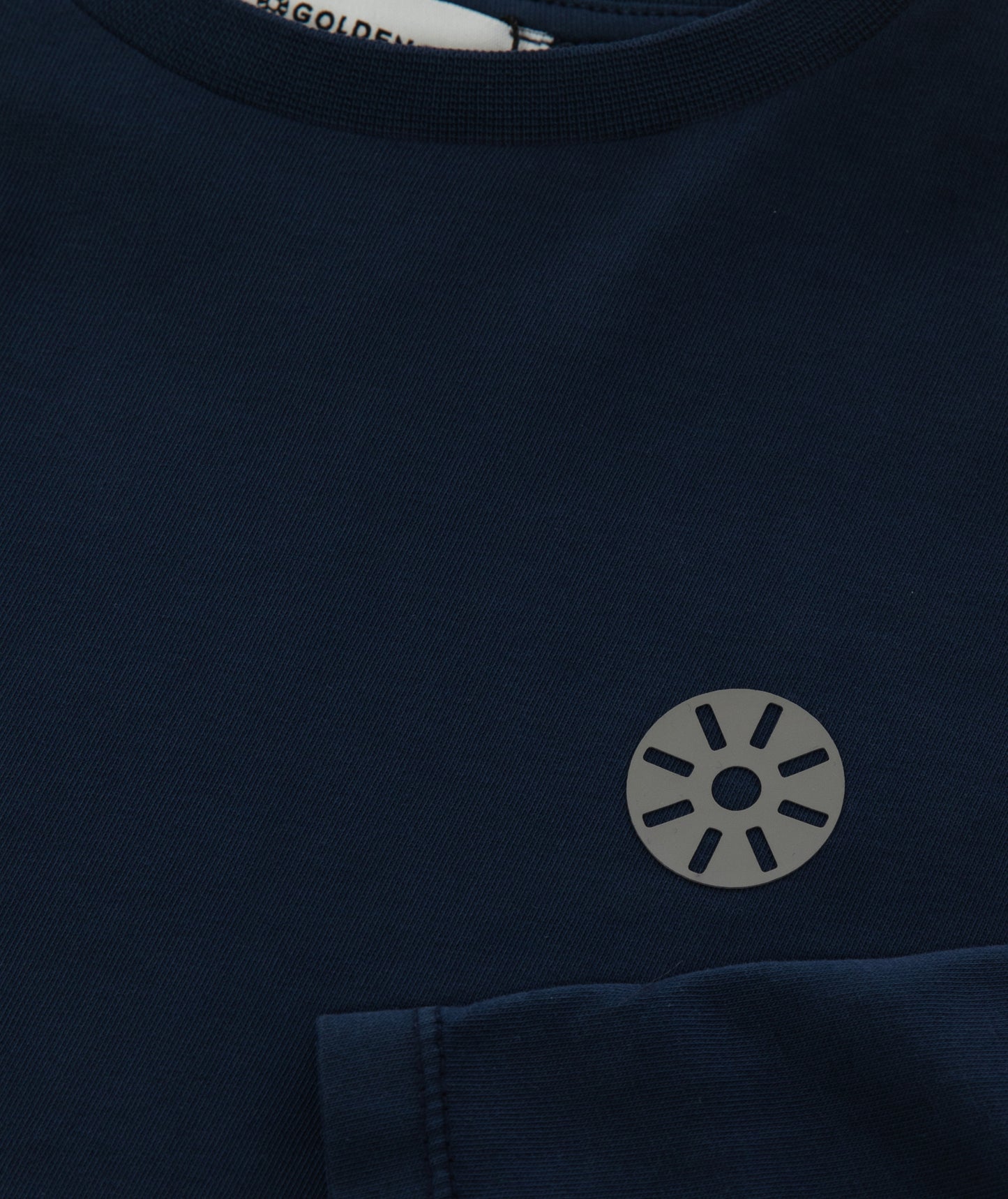 Close-up of Goldencubs gray circular logo printed on smooth navy cotton fabric of the long sleeve T-shirt.