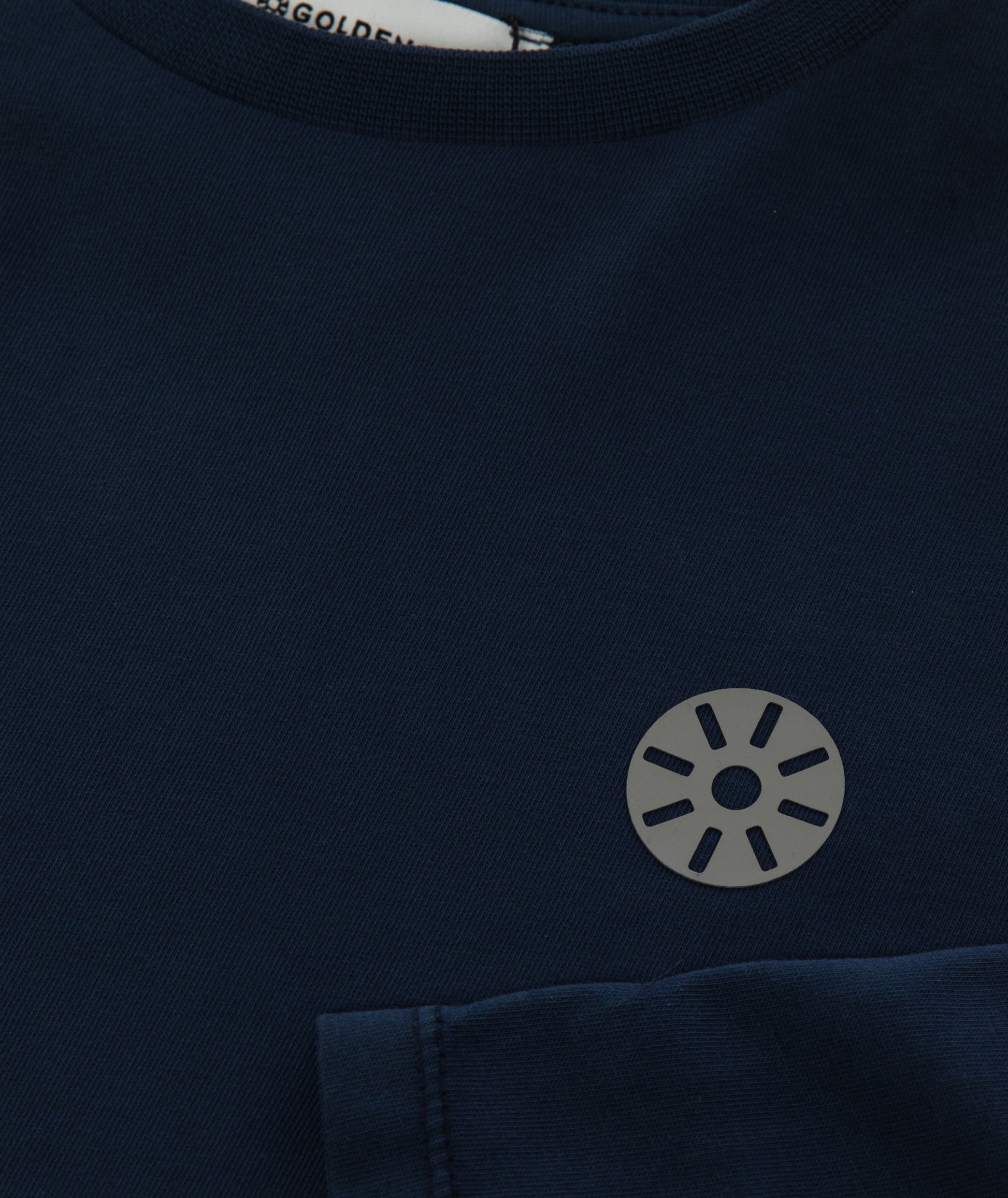 Close-up of Goldencubs gray circular logo printed on smooth navy cotton fabric of the long sleeve T-shirt.