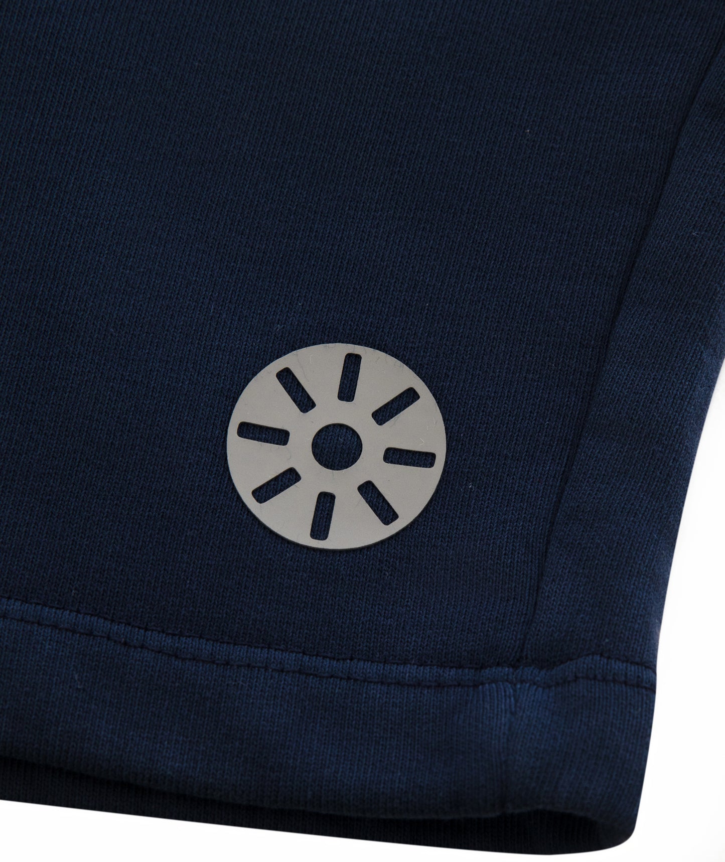 Close-up of Goldencubs gray circular logo printed on smooth navy cotton fabric near hem.