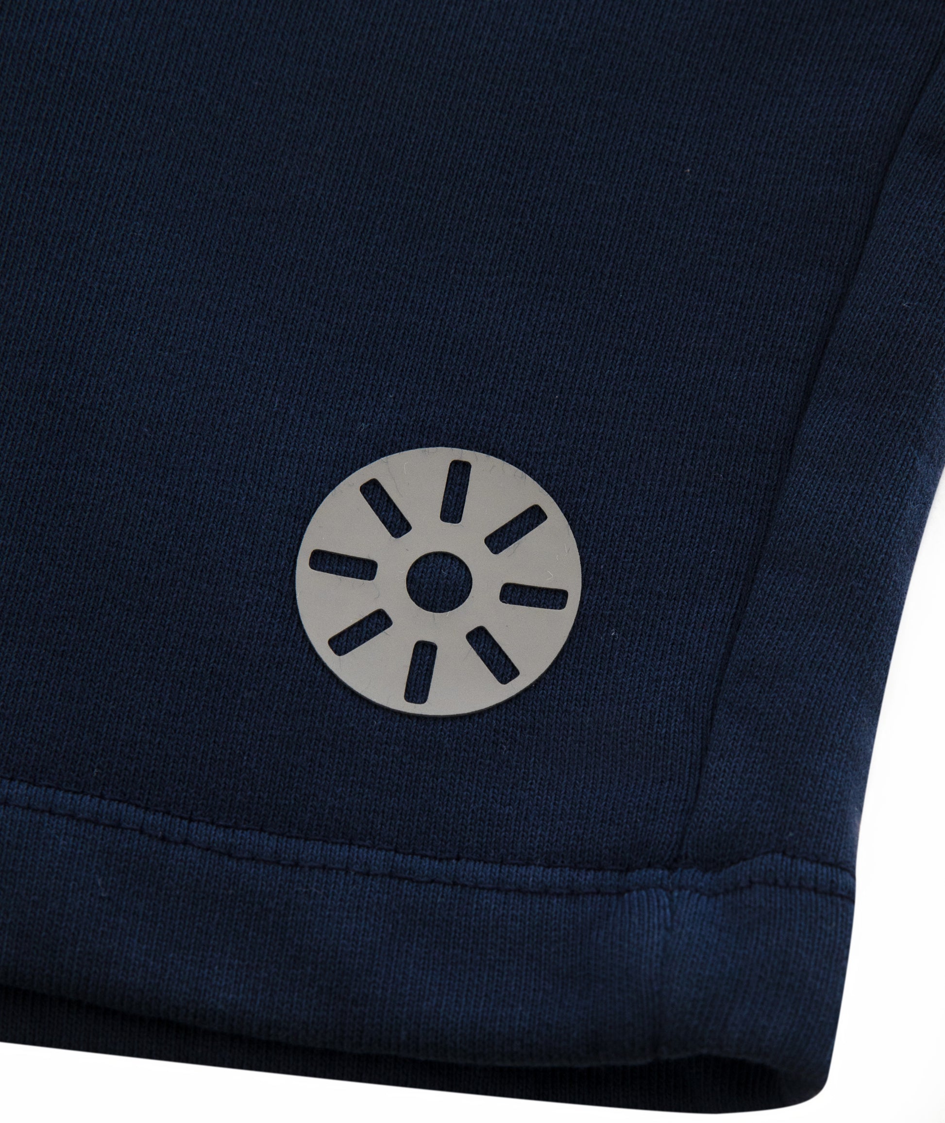 Close-up of Goldencubs gray circular logo printed on smooth navy cotton fabric near hem.