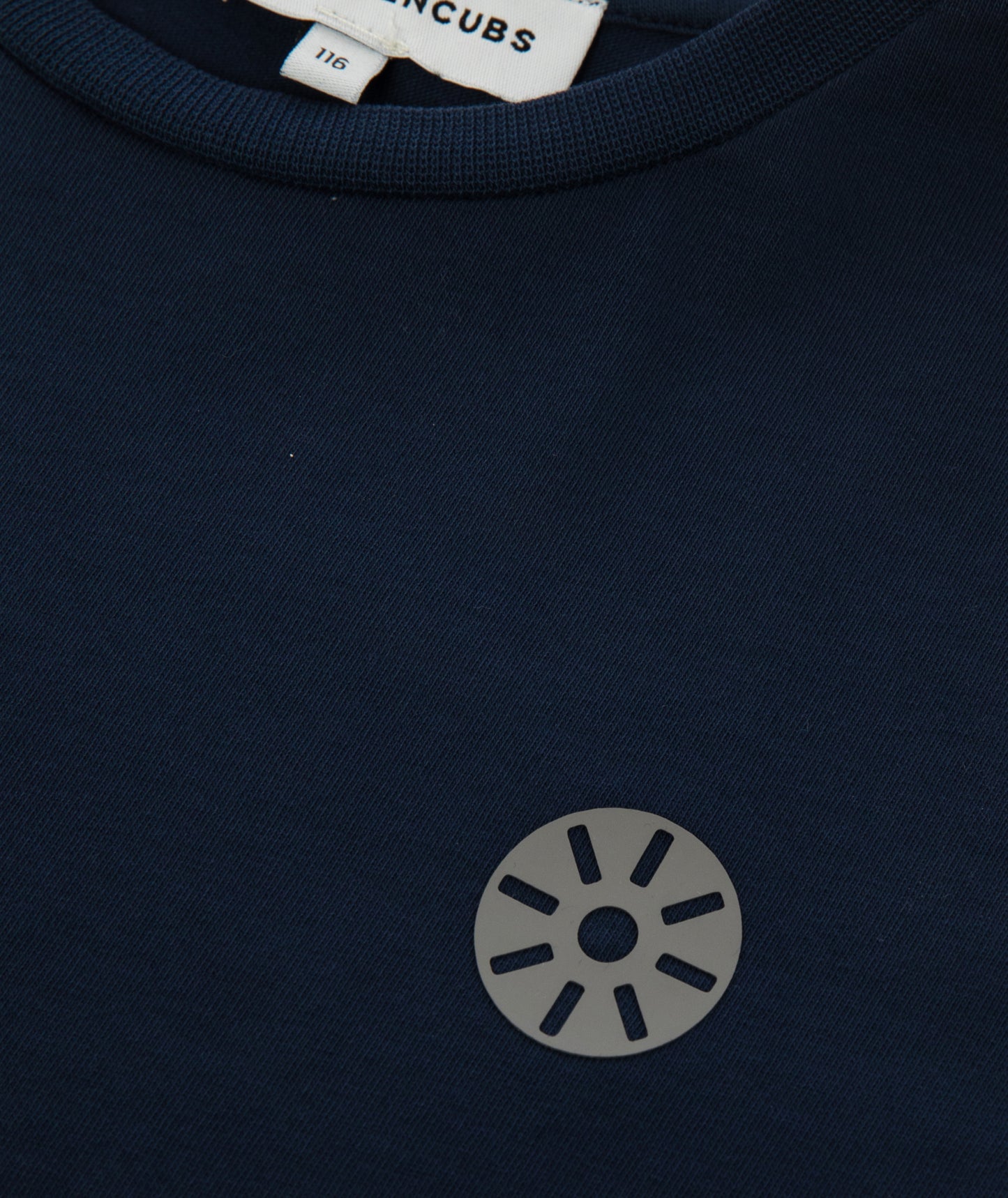 Close-up of Goldencubs gray circular logo printed on soft navy cotton T-shirt fabric near the neckline.