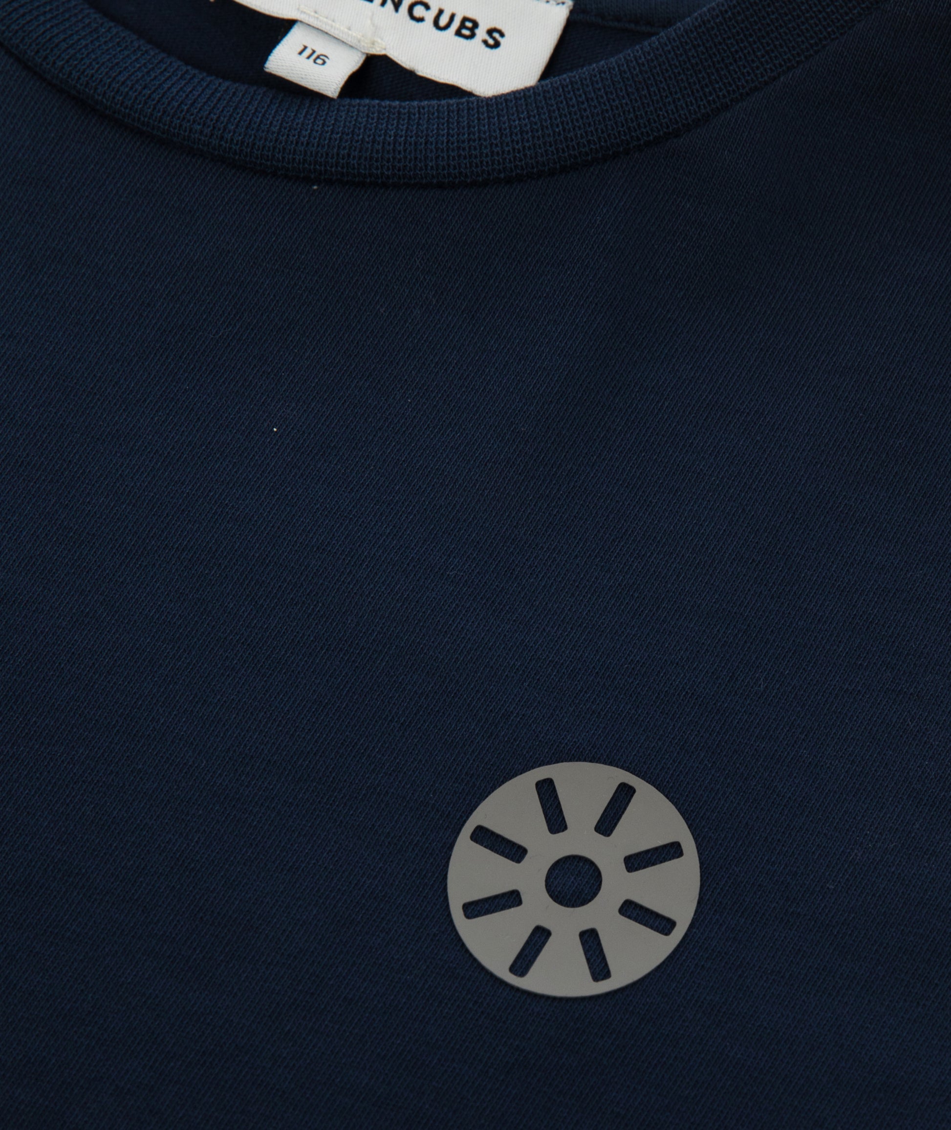 Close-up of Goldencubs gray circular logo printed on soft navy cotton T-shirt fabric near the neckline.