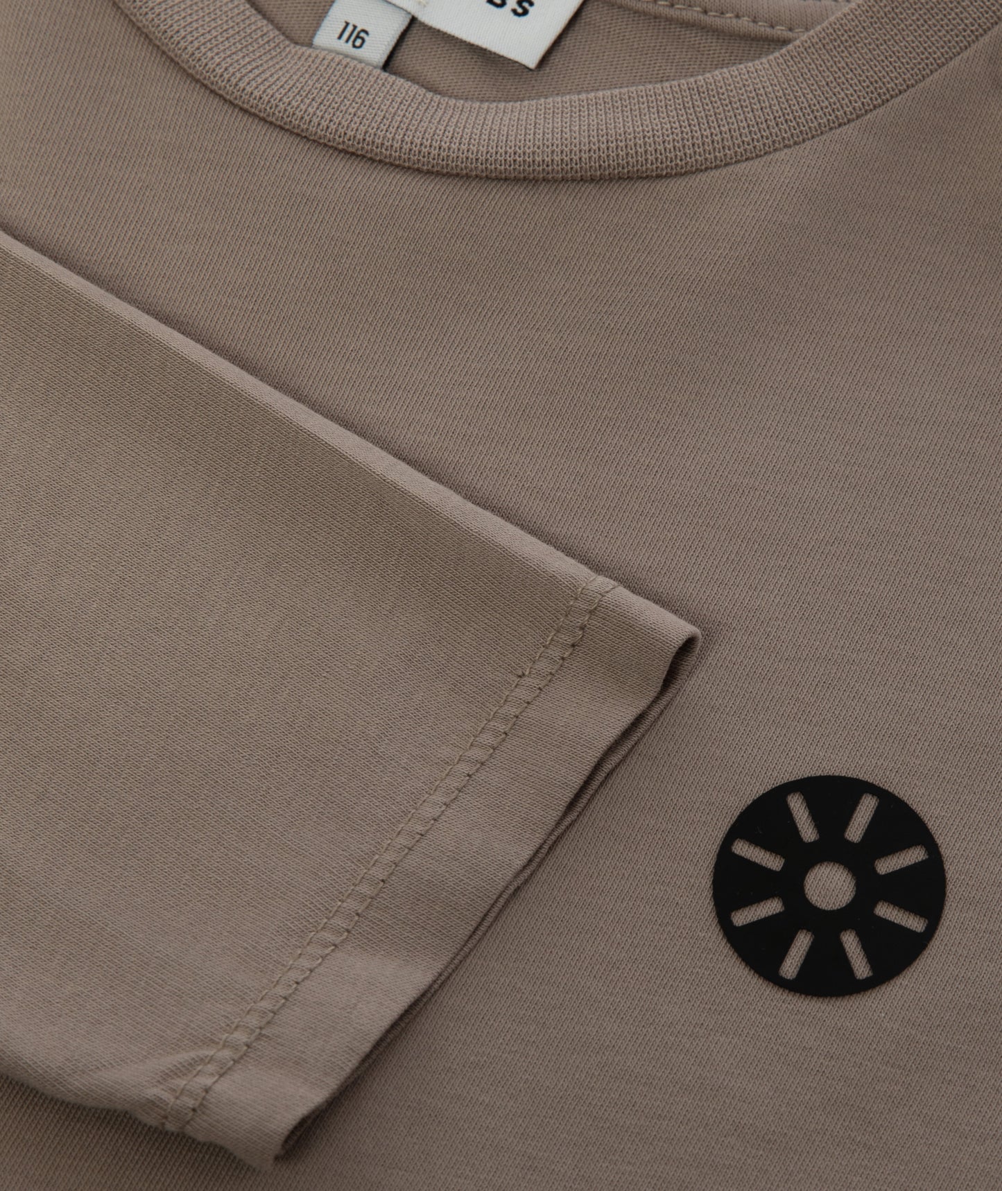 Close-up of Goldencubs black circular logo printed on smooth taupe cotton long sleeve fabric.