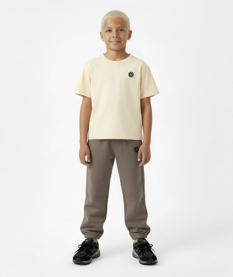 Front view of boy wearing Goldencubs cream cotton T-shirt paired with taupe sweatpants — breathable, minimalist, and cozy outfit for boys.