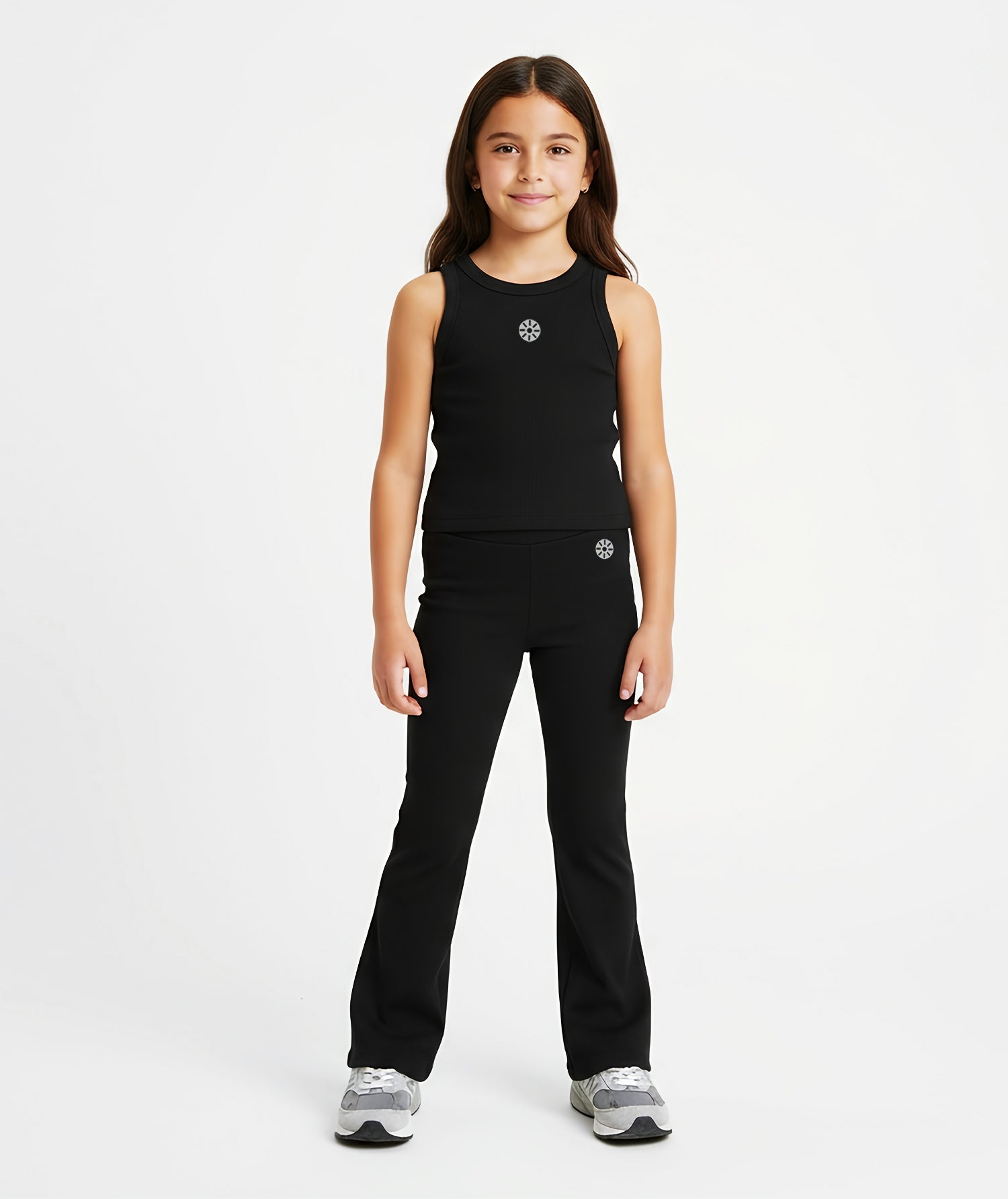 Girl wearing Goldencubs black cotton flared pants with reflective circular logo, paired with matching tank top and sneakers.