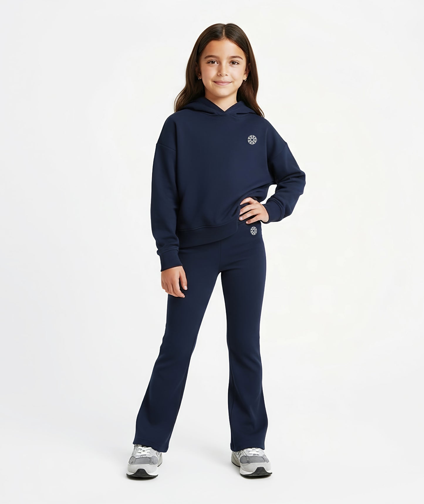Girl wearing Goldencubs navy cotton flared pants with black circular logo, styled with matching hoodie and gray sneakers.