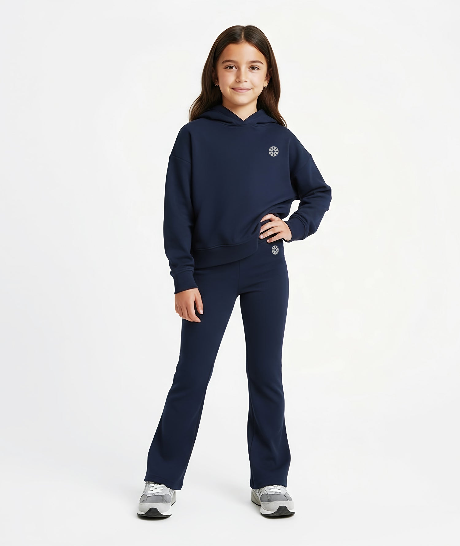 Girl wearing Goldencubs navy cotton flared pants with black circular logo, styled with matching hoodie and gray sneakers.
