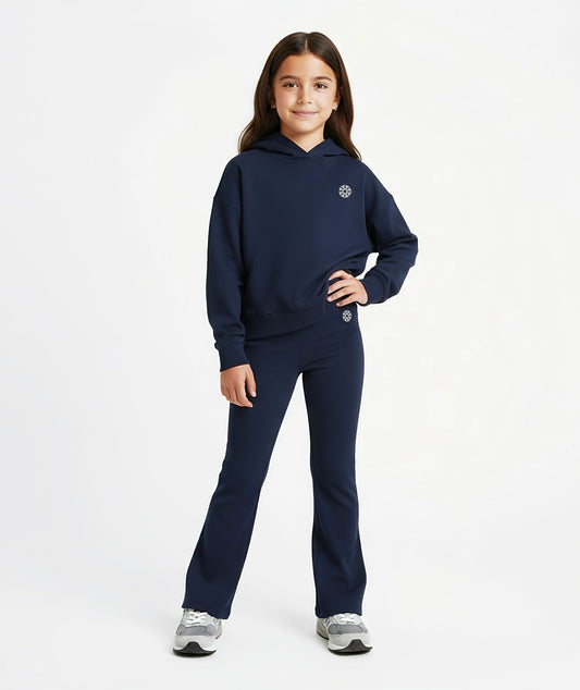 Girl wearing Goldencubs navy cotton flared pants with black circular logo, styled with matching hoodie and gray sneakers.