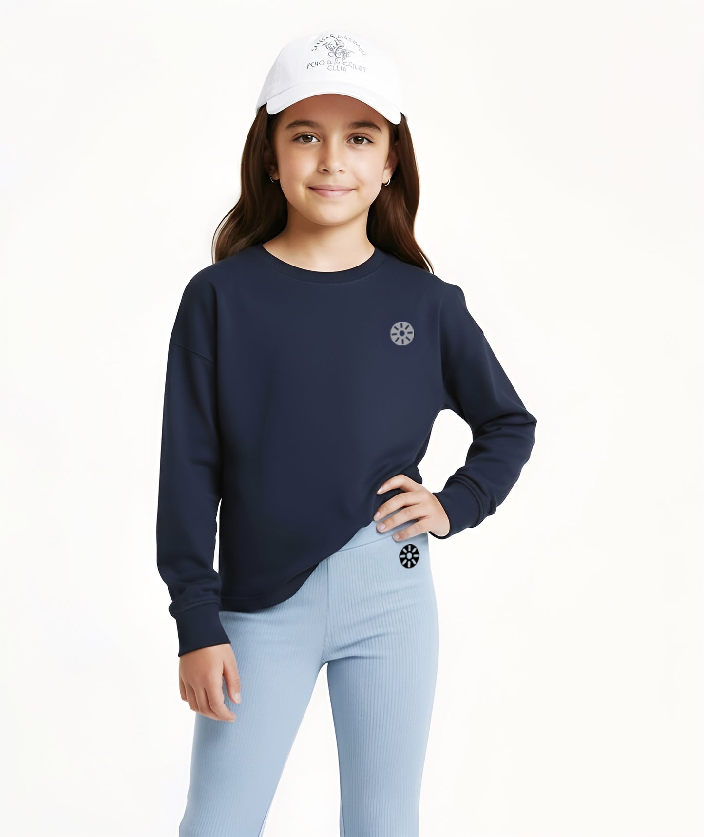 Girl wearing Goldencubs navy cotton long sleeve T-shirt and light blue flared pants with white cap, styled for sporty casual wear.