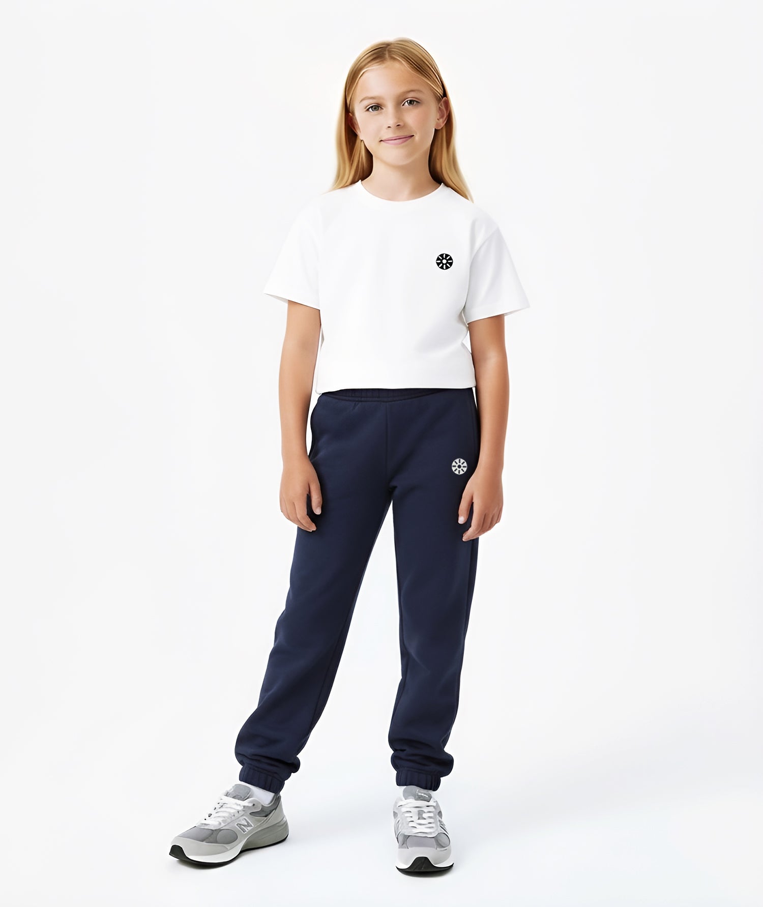 Girl wearing Goldencubs navy cotton sweatpants with black circular logo, styled with white T-shirt and gray sneakers.