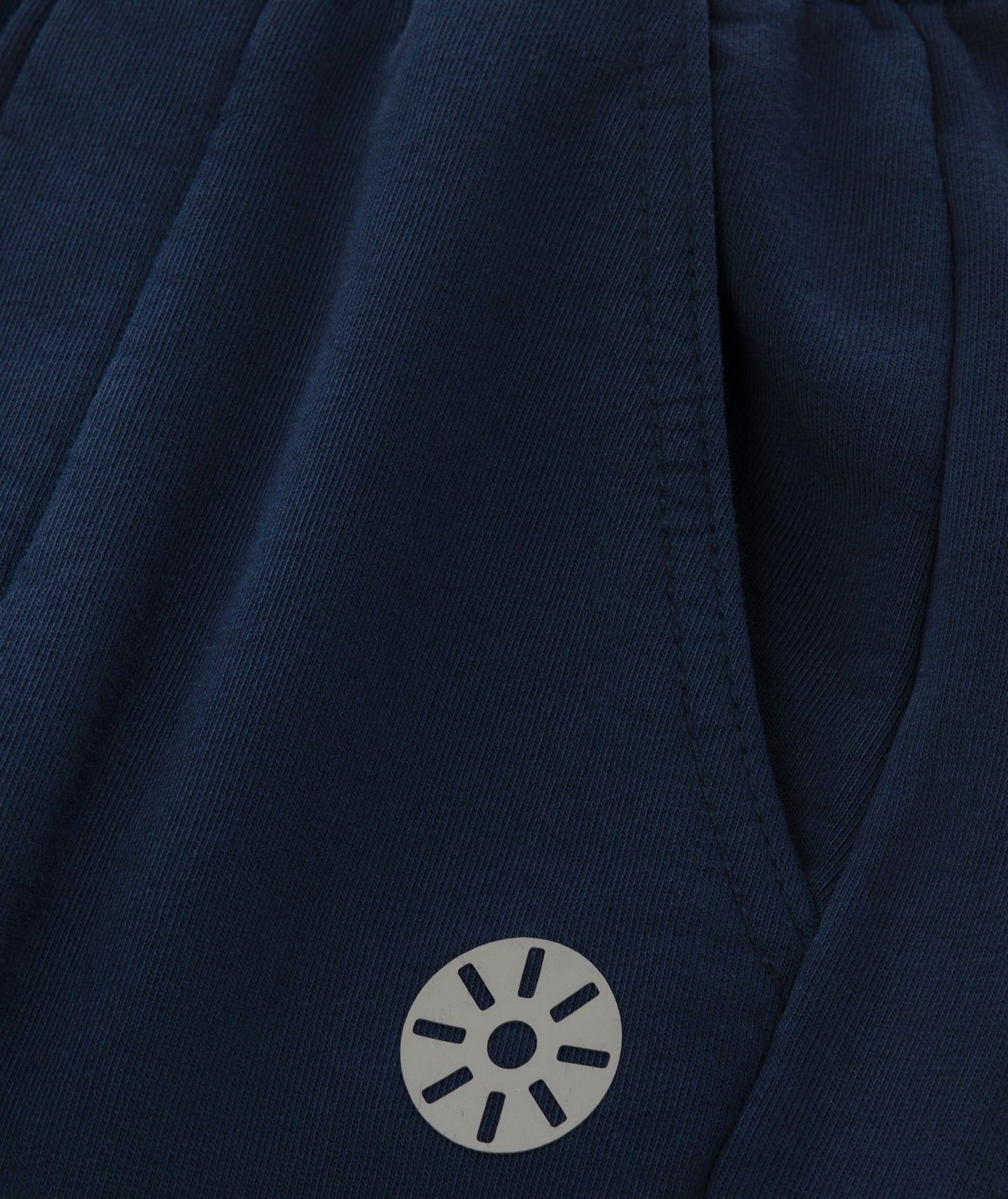 Close-up of Goldencubs black circular logo printed on smooth navy cotton fabric near the pocket.