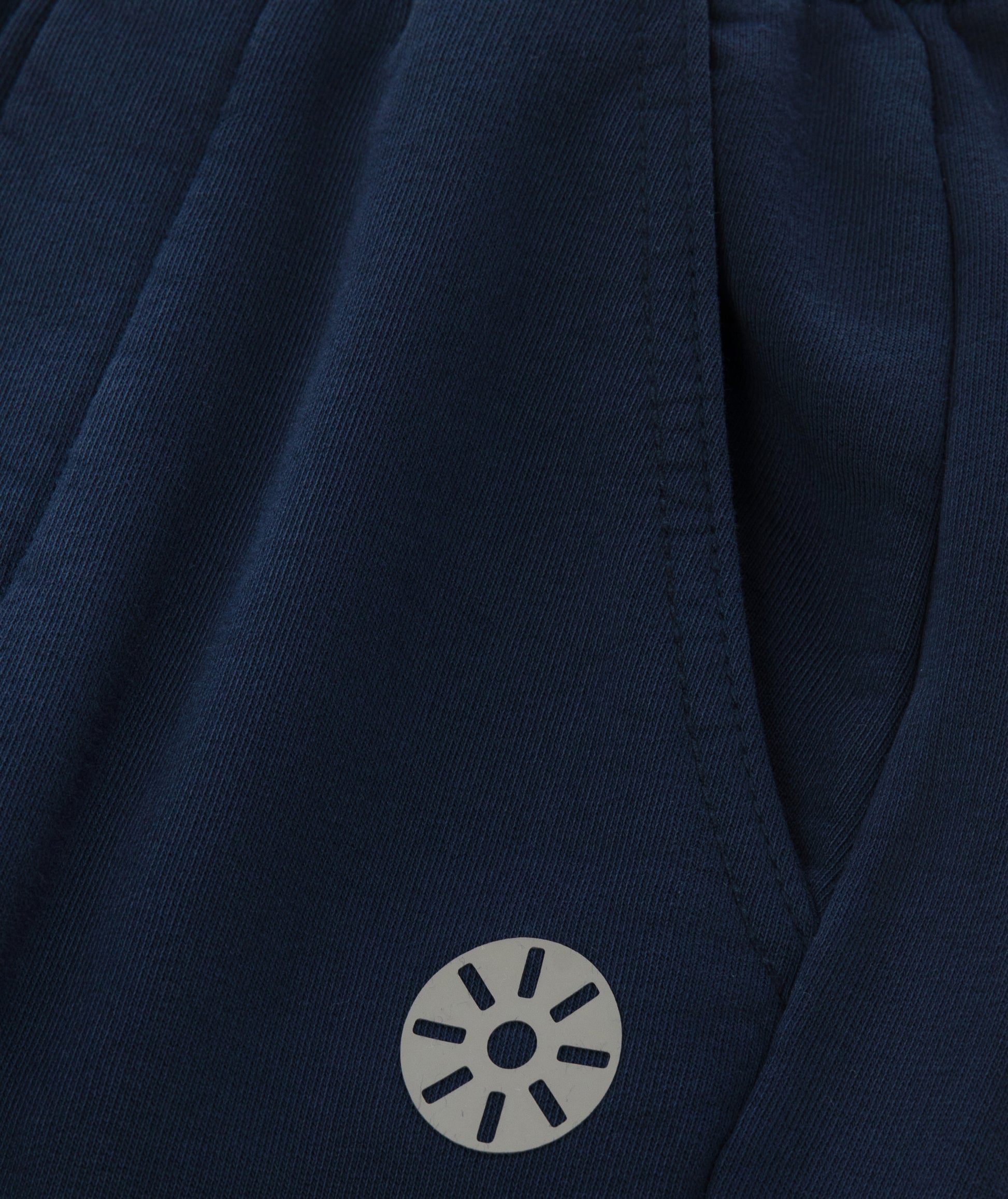 Close-up of Goldencubs black circular logo printed on smooth navy cotton fabric near the pocket.