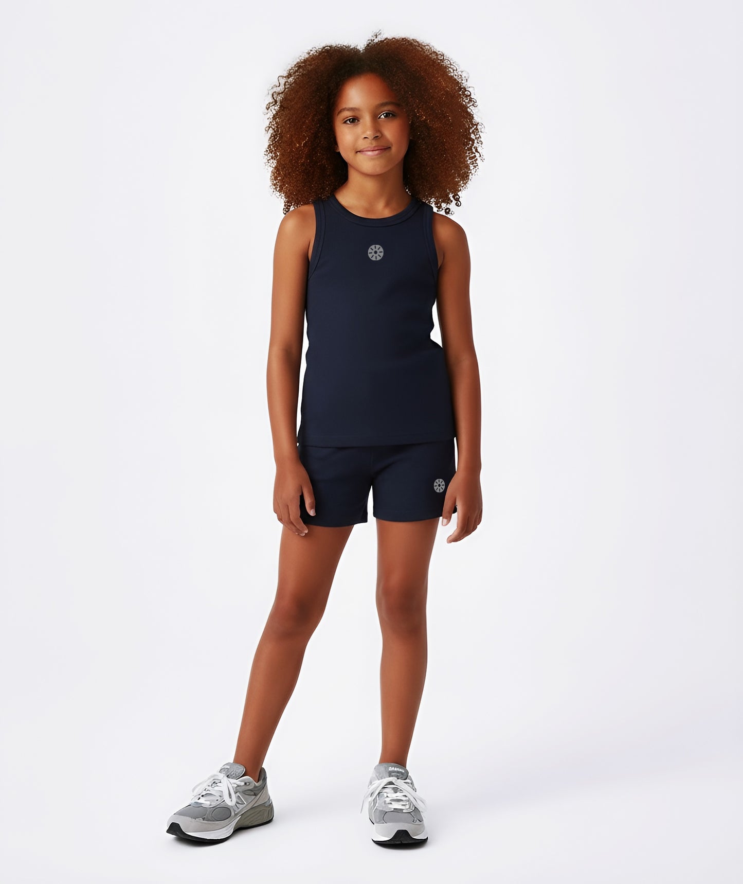 Girl wearing Goldencubs navy cotton tank top with gray circular logo, paired with matching navy shorts and gray sneakers.