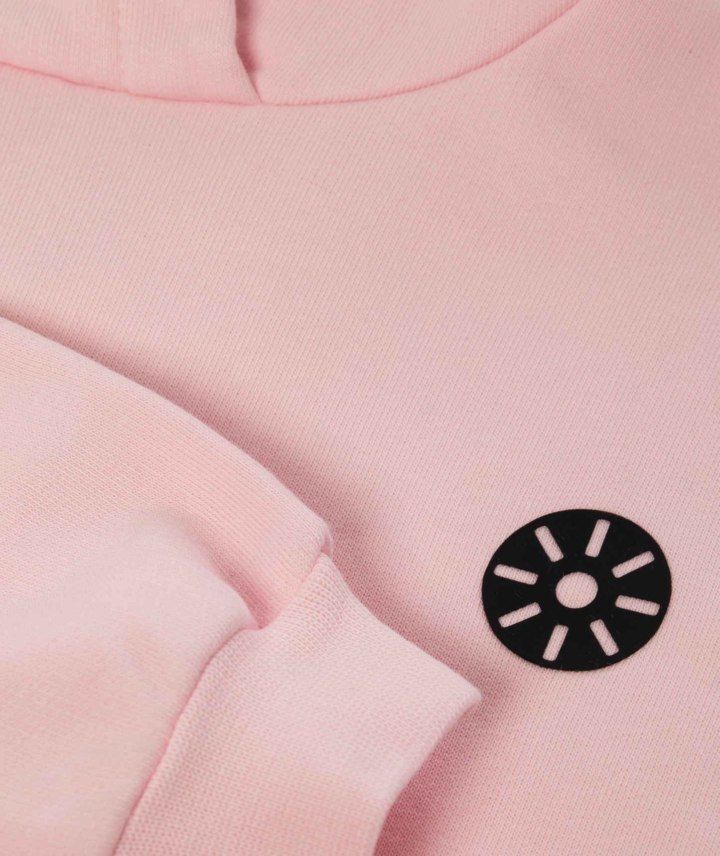 Close-up of Goldencubs black circular logo printed on soft pink cotton hoodie fabric.