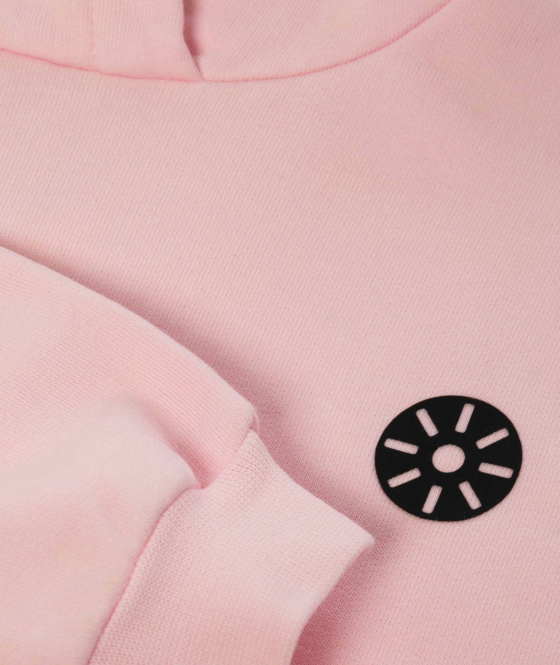 Close-up of Goldencubs black circular logo printed on soft pink cotton hoodie fabric.