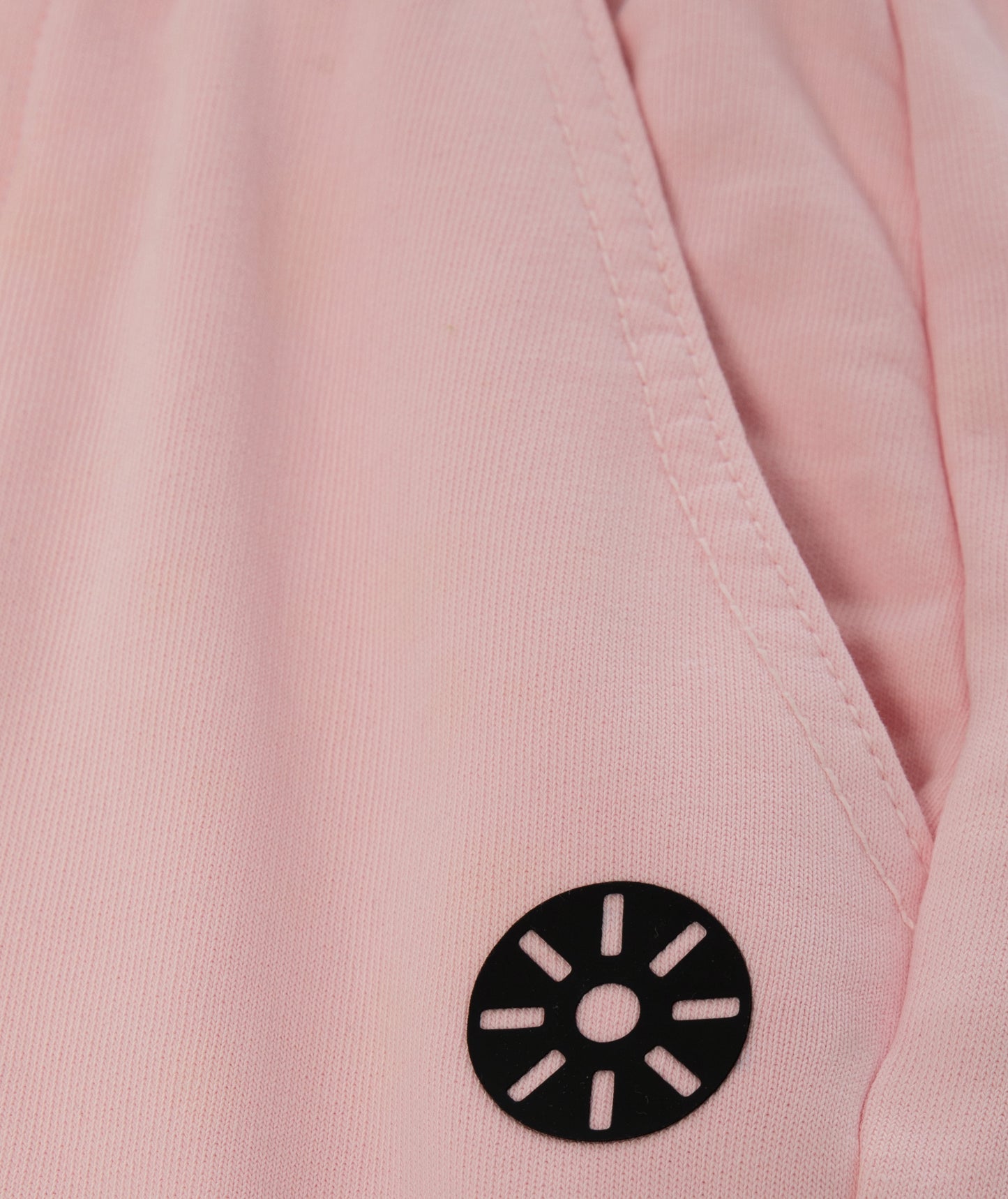Close-up of Goldencubs black circular logo printed on soft pink cotton sweatpants fabric.