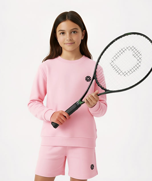 Girl holding a tennis racket while wearing Goldencubs pink cotton sweatshirt and shorts, showing sporty style.