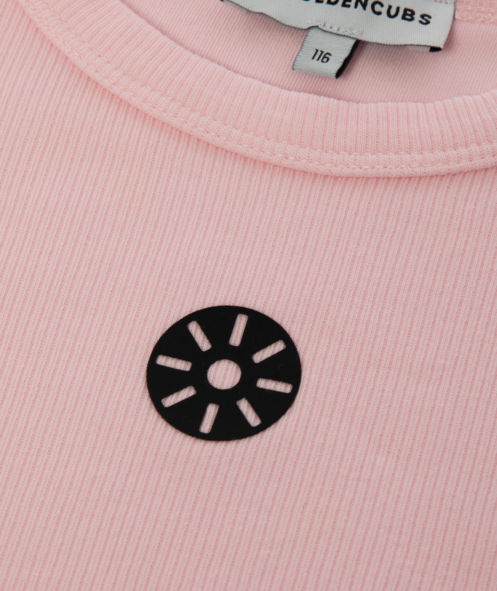 Close-up of Goldencubs black circular logo printed on ribbed pink cotton fabric near neckline.