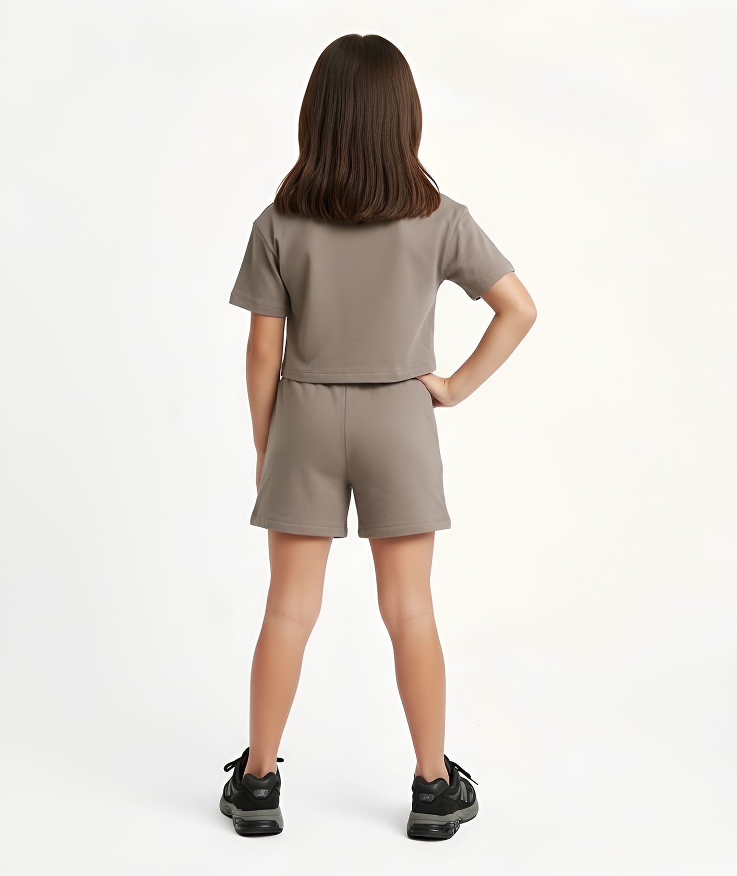 Back view of girl wearing Goldencubs taupe cotton shorts, showing elastic waistband and relaxed fit.