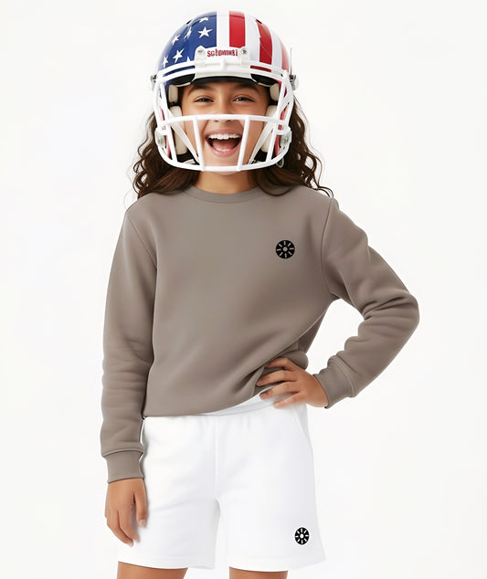 Girl wearing Goldencubs taupe cotton sweatshirt with black circular logo, styled with white shorts and a sporty helmet.