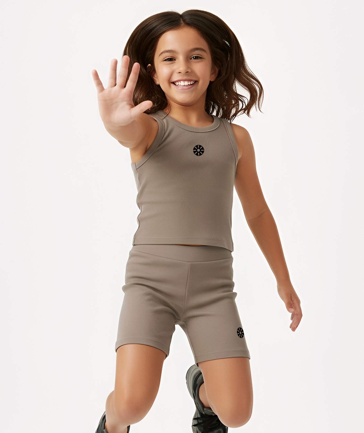 Smiling girl jumping playfully in Goldencubs taupe cotton tank top and shorts, highlighting comfort and movement.