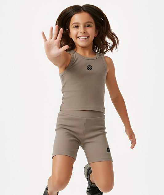 Smiling girl jumping playfully in Goldencubs taupe cotton tank top and shorts, highlighting comfort and movement.