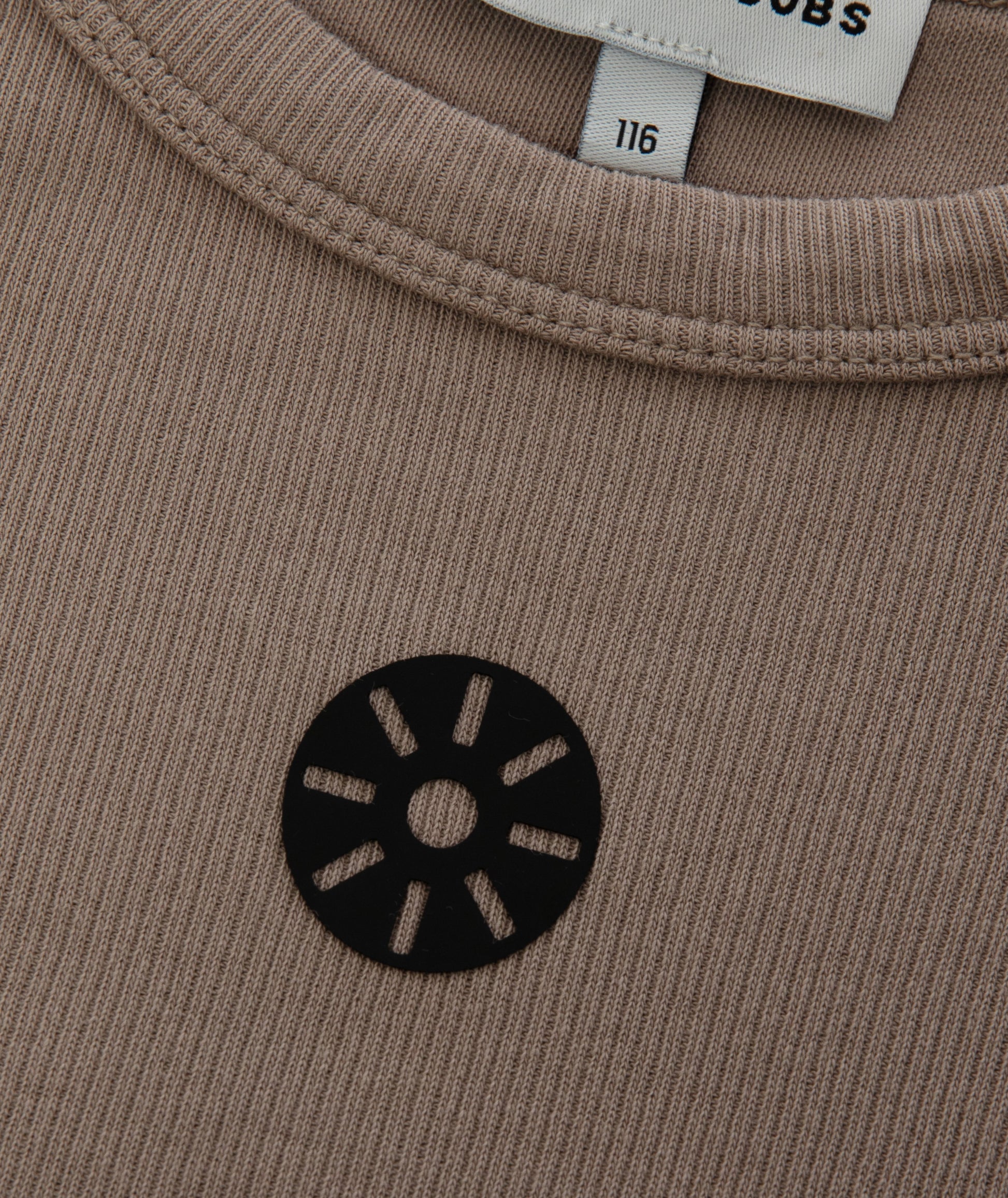 Close-up of Goldencubs signature black circular logo printed on ribbed taupe cotton fabric near the neckline.