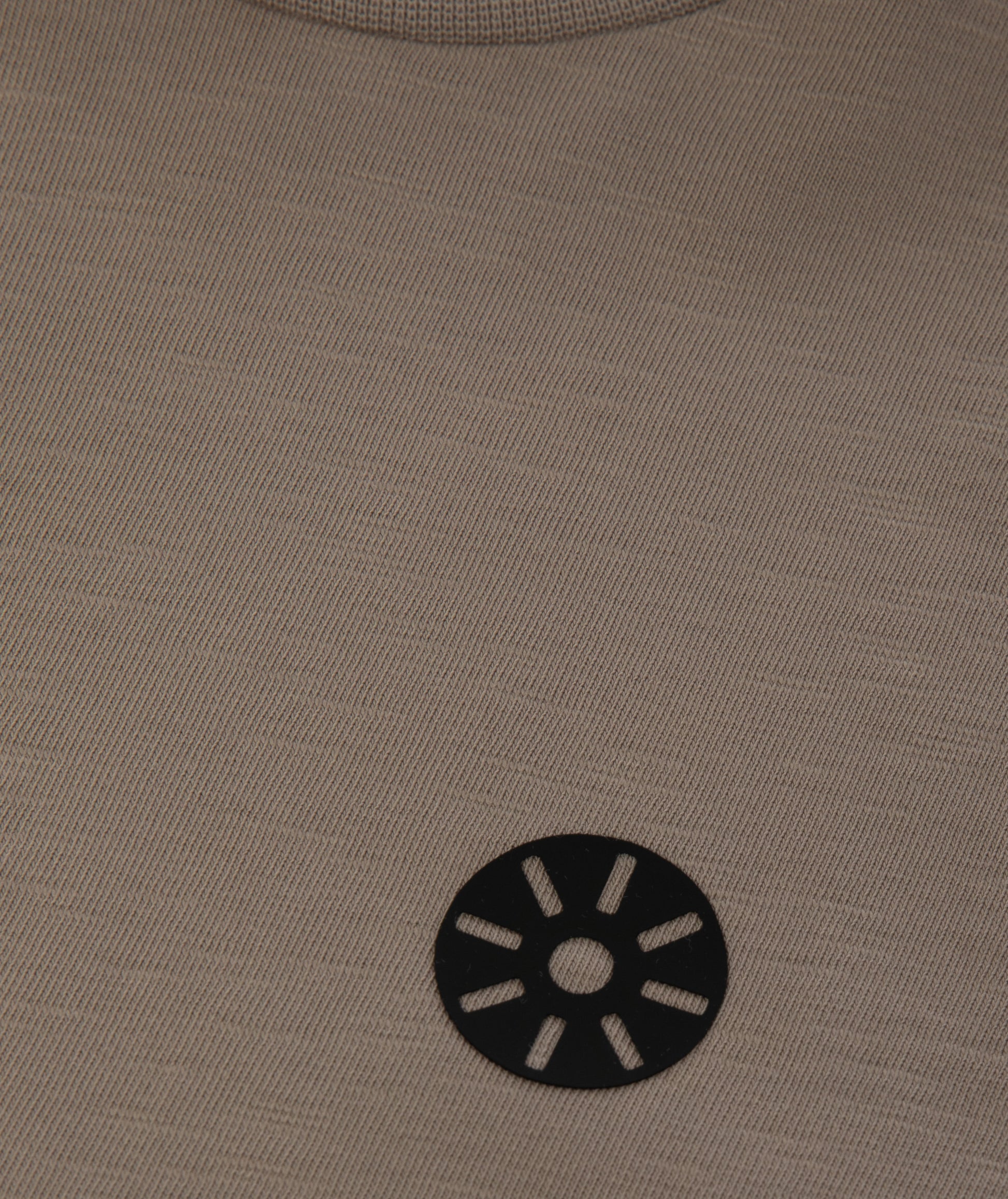 Close-up of Goldencubs black circular logo printed on soft taupe cotton fabric.