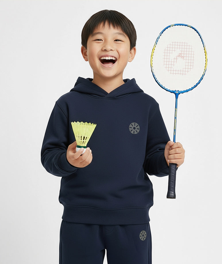 Smiling boy wearing Goldencubs navy cotton hoodie and sweatpants, holding badminton shuttlecock — premium kids sportswear with soft cotton comfort.