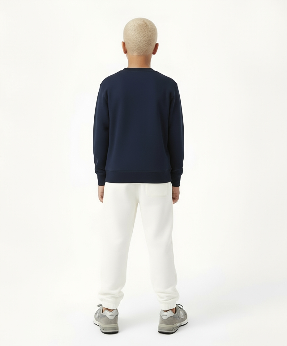 Back view of boy wearing Goldencubs navy cotton long sleeve T-shirt and white sweatpants — minimal and relaxed athleisurewear for kids.