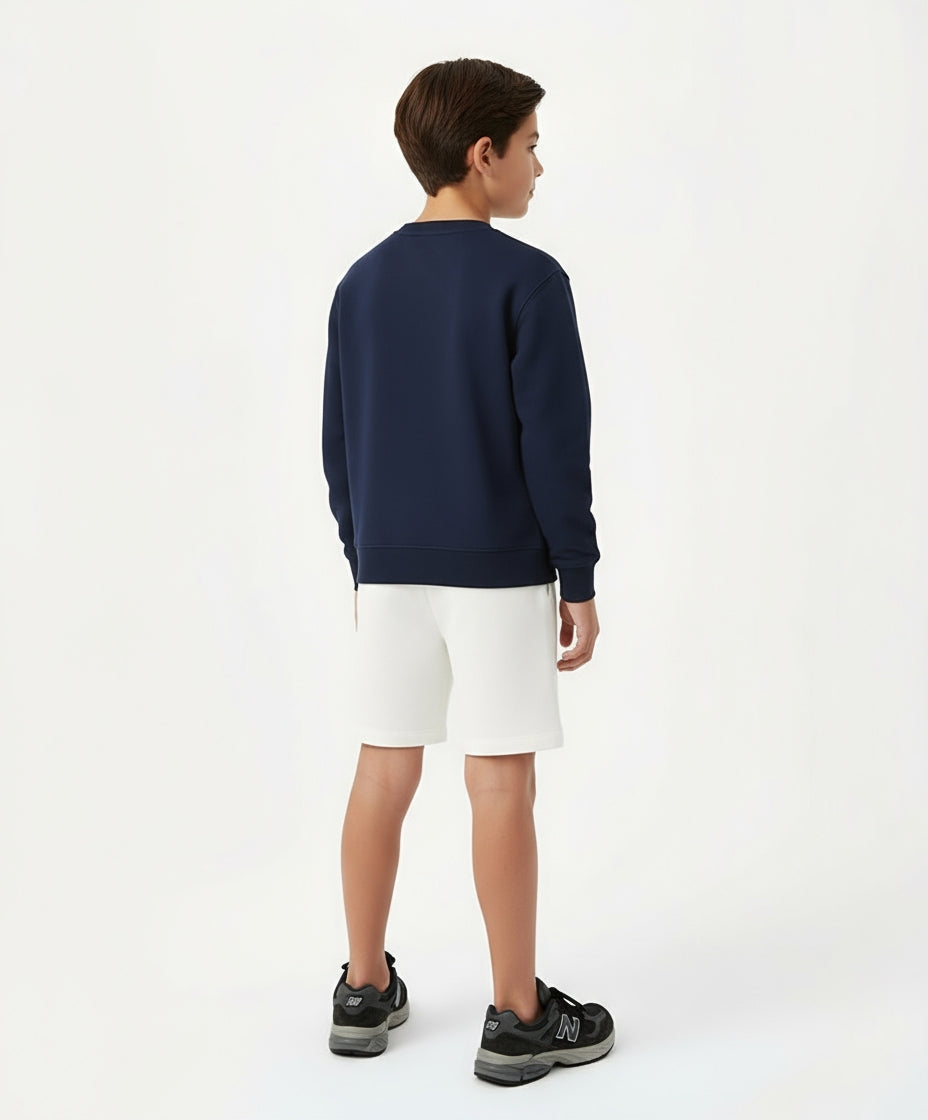 Back view of boy wearing Goldencubs navy cotton sweatshirt paired with white shorts — minimal and sporty kidswear design.