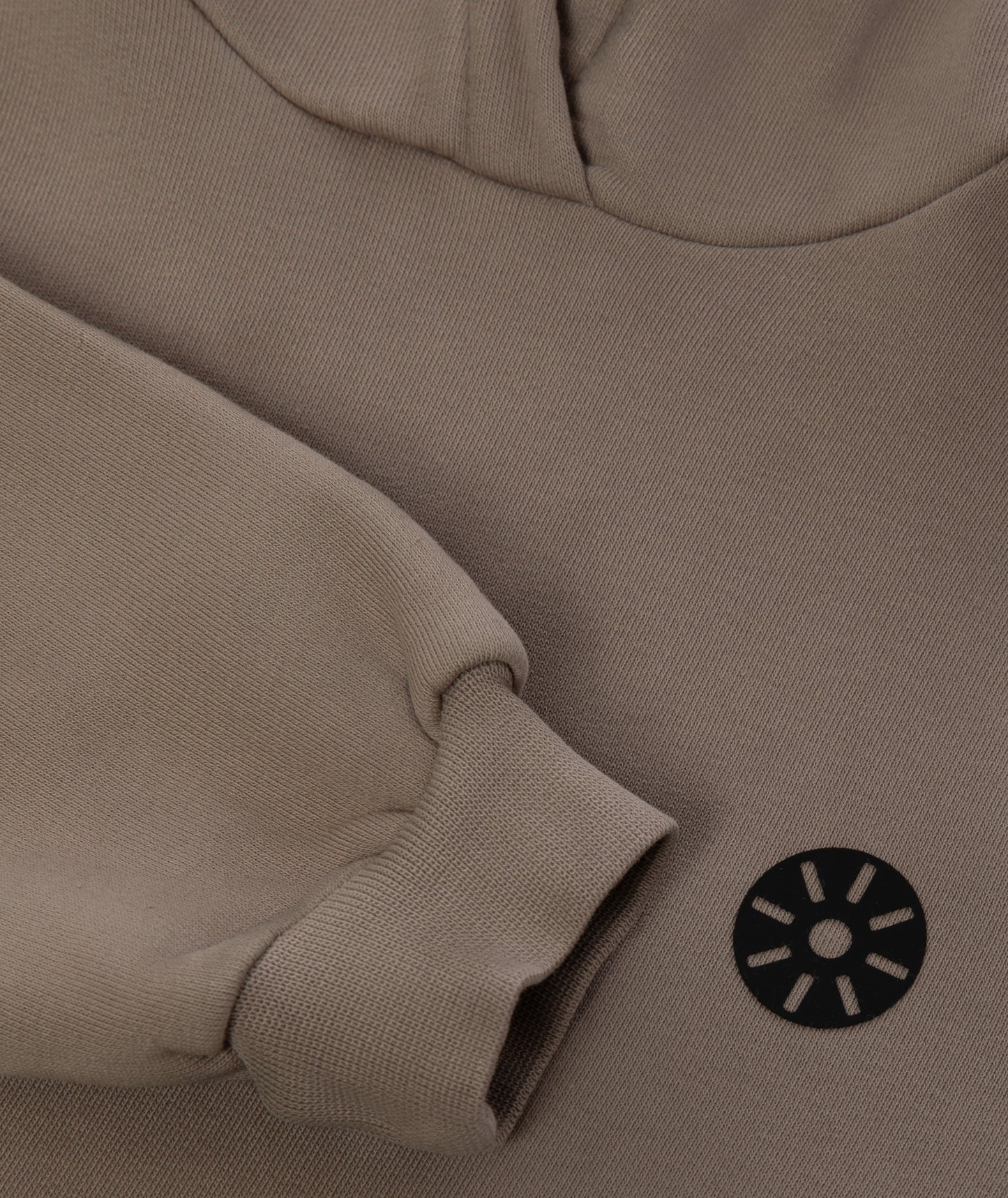 Close-up of Goldencubs taupe cotton hoodie sleeve and fabric texture with black circular logo patch — premium quality kids athleisurewear.