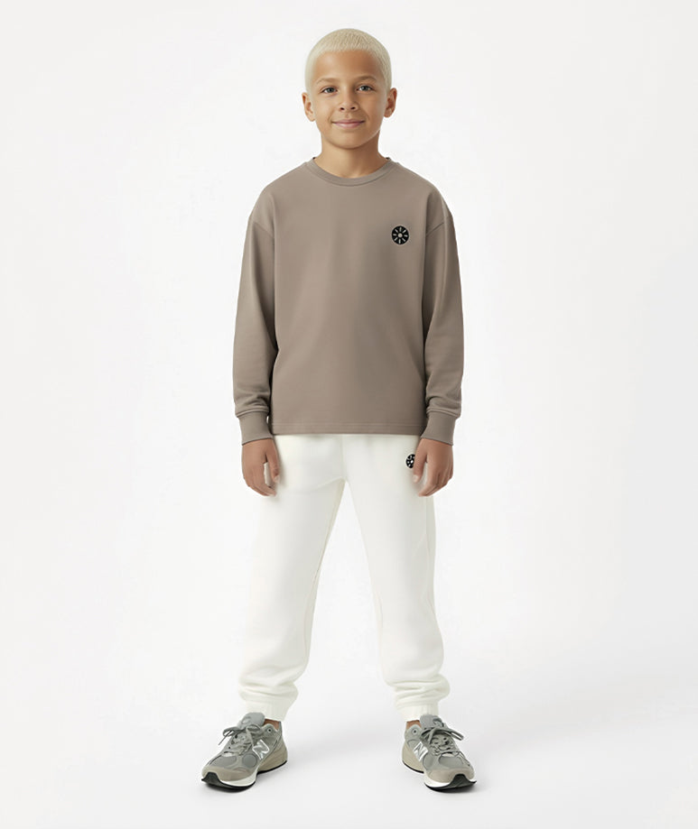 Front view of Goldencubs taupe cotton boys long sleeve T-shirt with round neckline and black logo patch — soft and stylish everyday top.