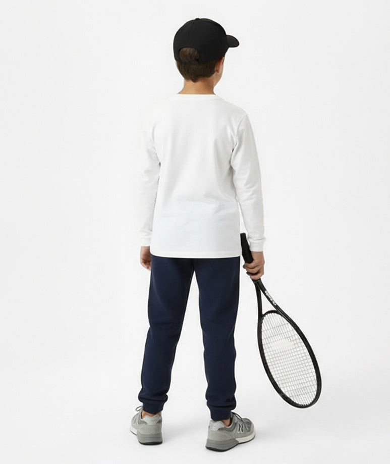 Back view of boy wearing Goldencubs white cotton long sleeve T-shirt with navy sweatpants and black cap — sporty and modern kids outfit.