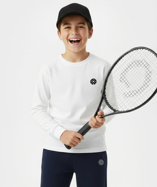 Smiling boy wearing Goldencubs white cotton long sleeve T-shirt and navy sweatpants, holding a tennis racket — comfortable and fashionable kids athleisure style.