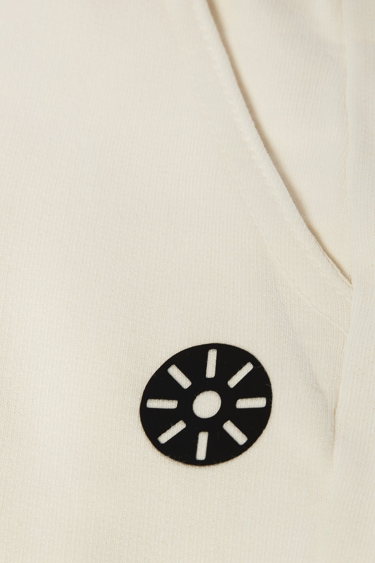 Close-up of Goldencubs white cotton boys sweatpants showing soft ribbed fabric and black circular logo patch — premium kids athleisure detail.