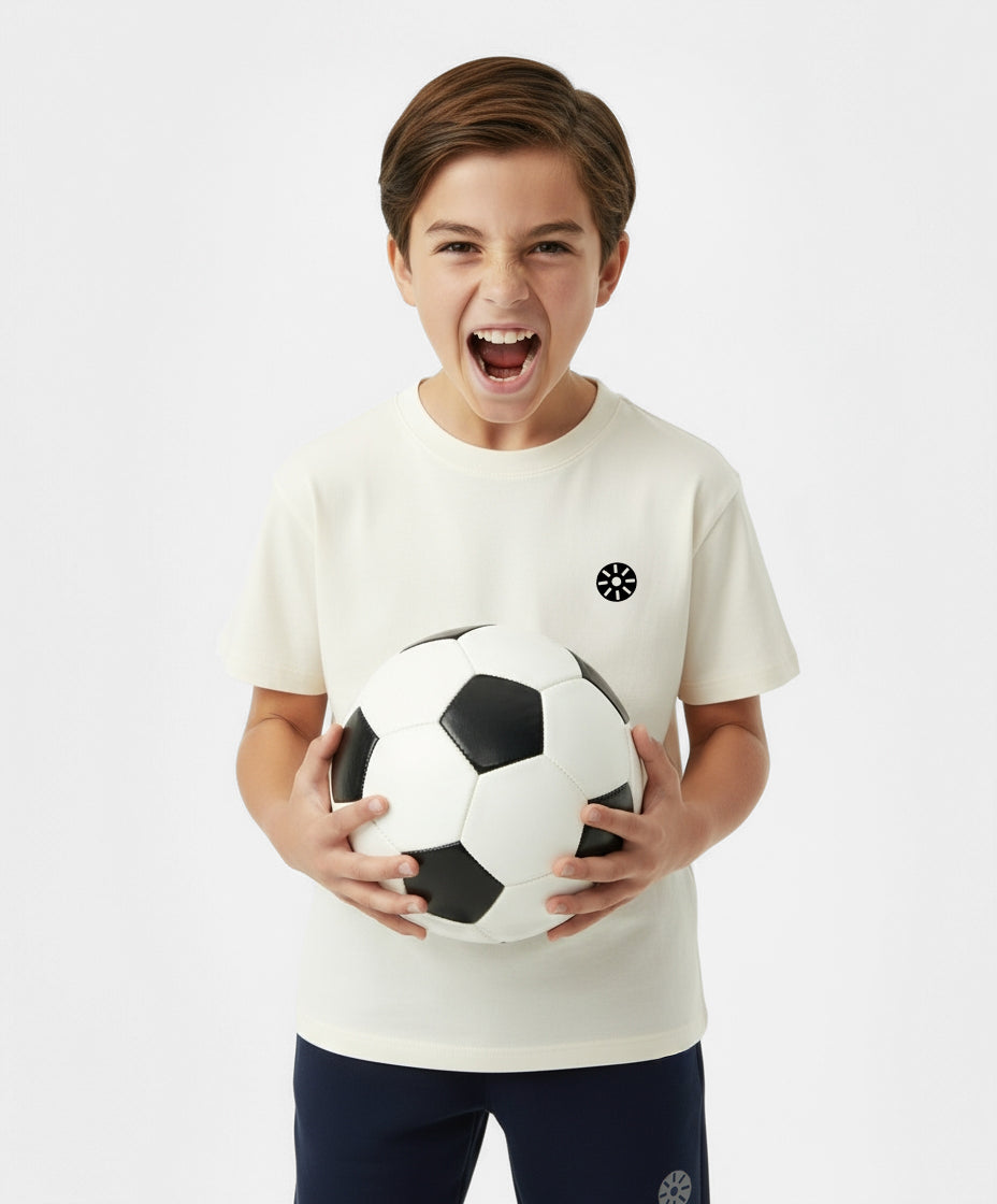 Smiling boy playing with soccer ball while wearing Goldencubs white cotton t-shirt — fun, soft, and breathable kids activewear.