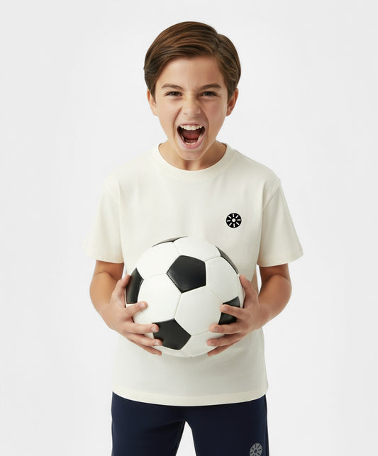 Smiling boy playing with soccer ball while wearing Goldencubs white cotton t-shirt — fun, soft, and breathable kids activewear.