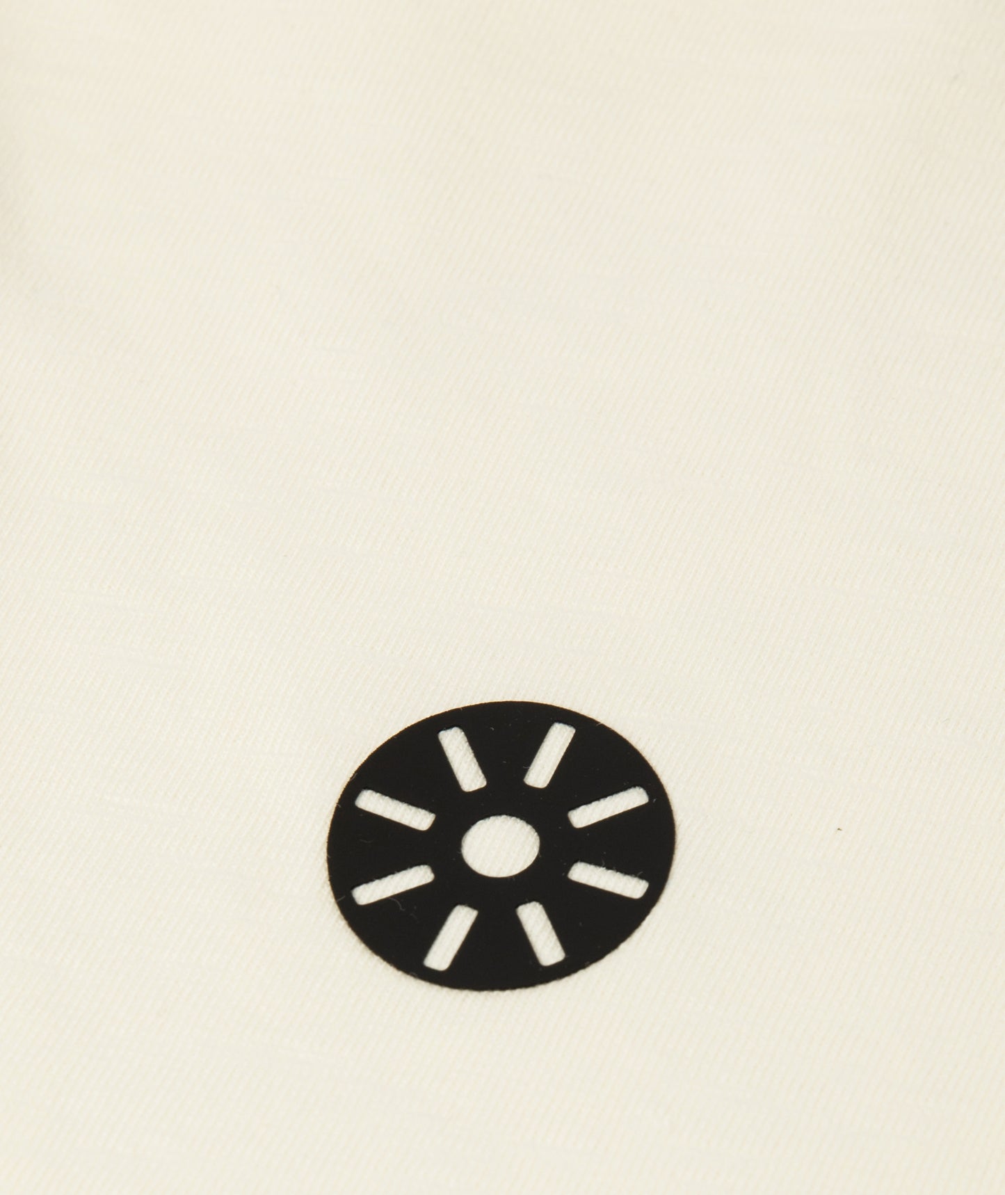 Close-up of Goldencubs white cotton cropped girls T-shirt showing smooth fabric texture and circular black logo patch detail.