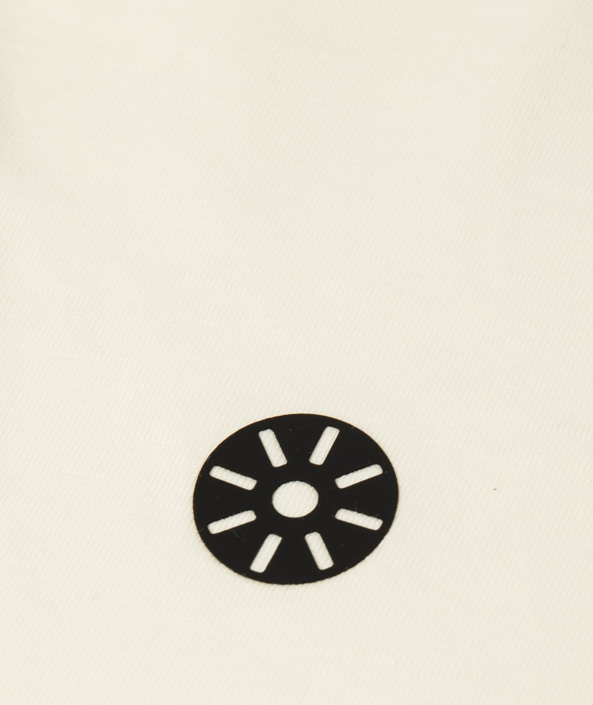 Close-up of Goldencubs white cotton cropped girls T-shirt showing smooth fabric texture and circular black logo patch detail.