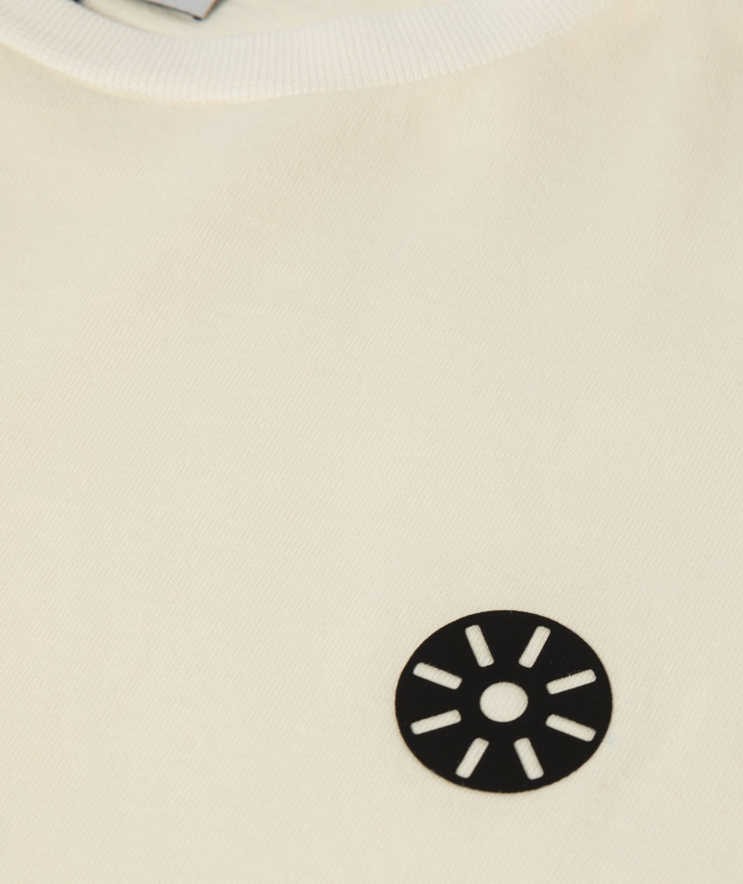 Close-up of Goldencubs white cotton girls long sleeve T-shirt showing ribbed neckline and black circular logo patch — premium kidswear detail shot.