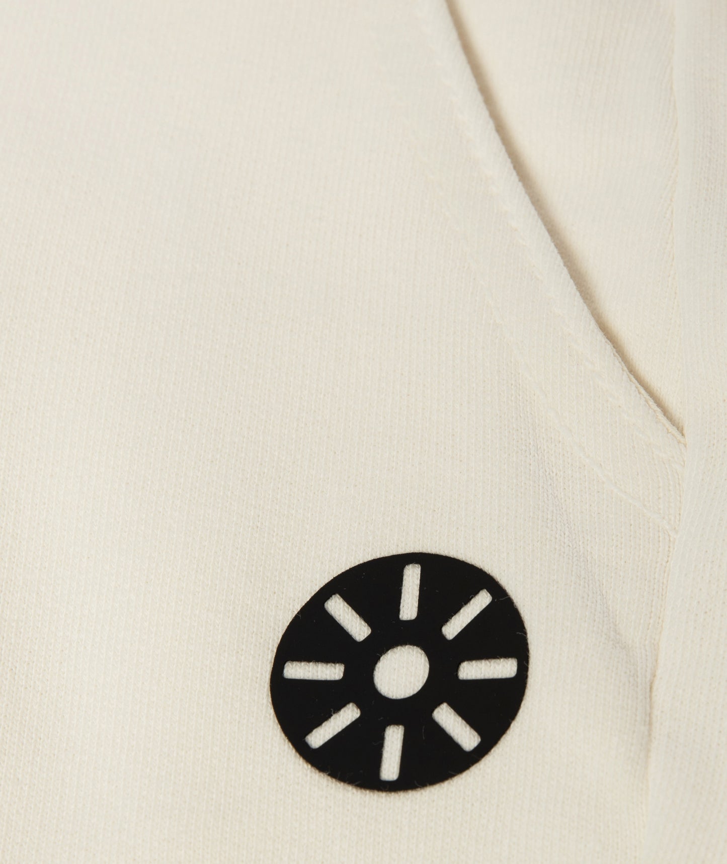 Close-up of Goldencubs white cotton girls sweatpants showing smooth ribbed fabric and circular black logo patch detail.