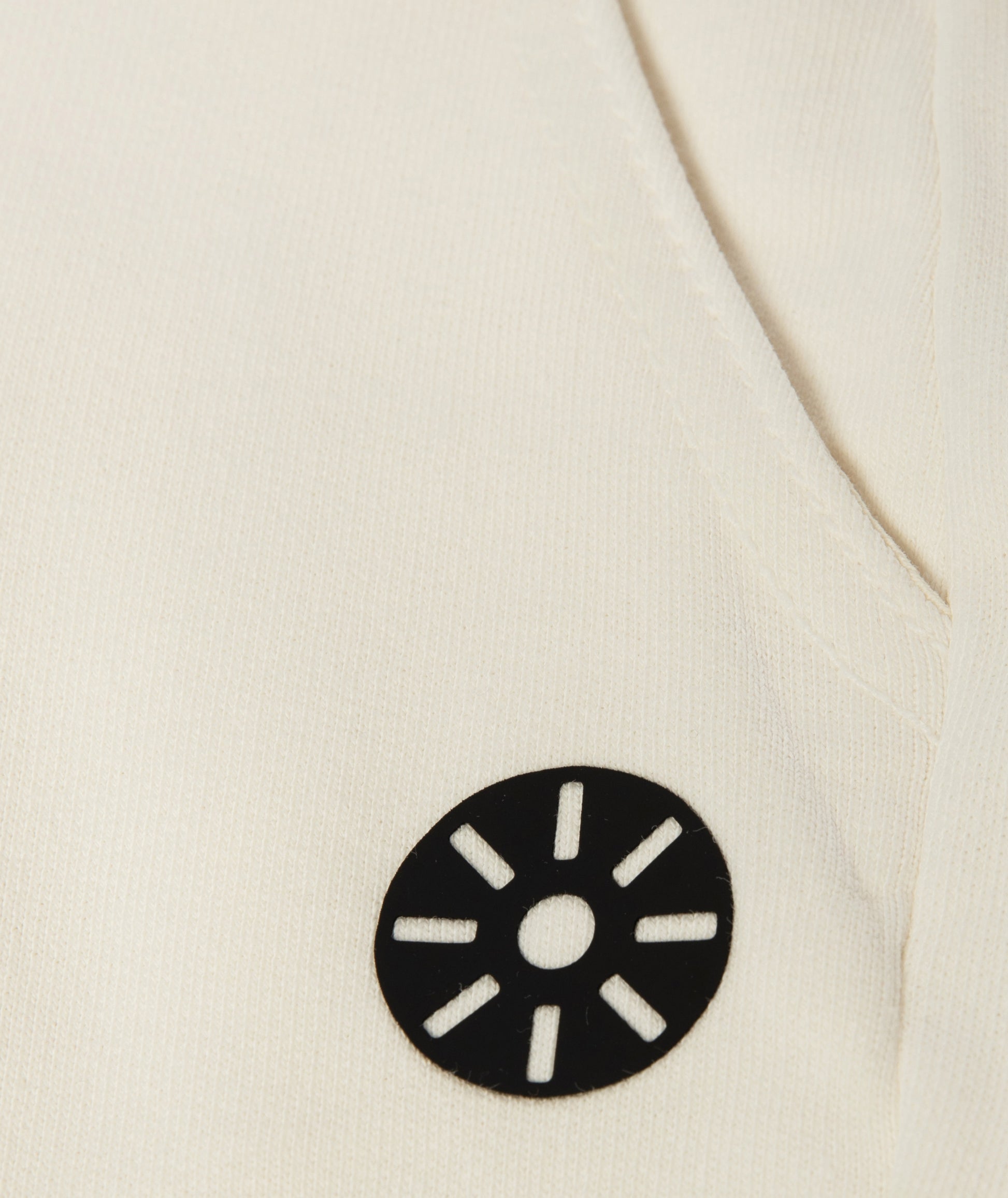 Close-up of Goldencubs white cotton girls sweatpants showing smooth ribbed fabric and circular black logo patch detail.
