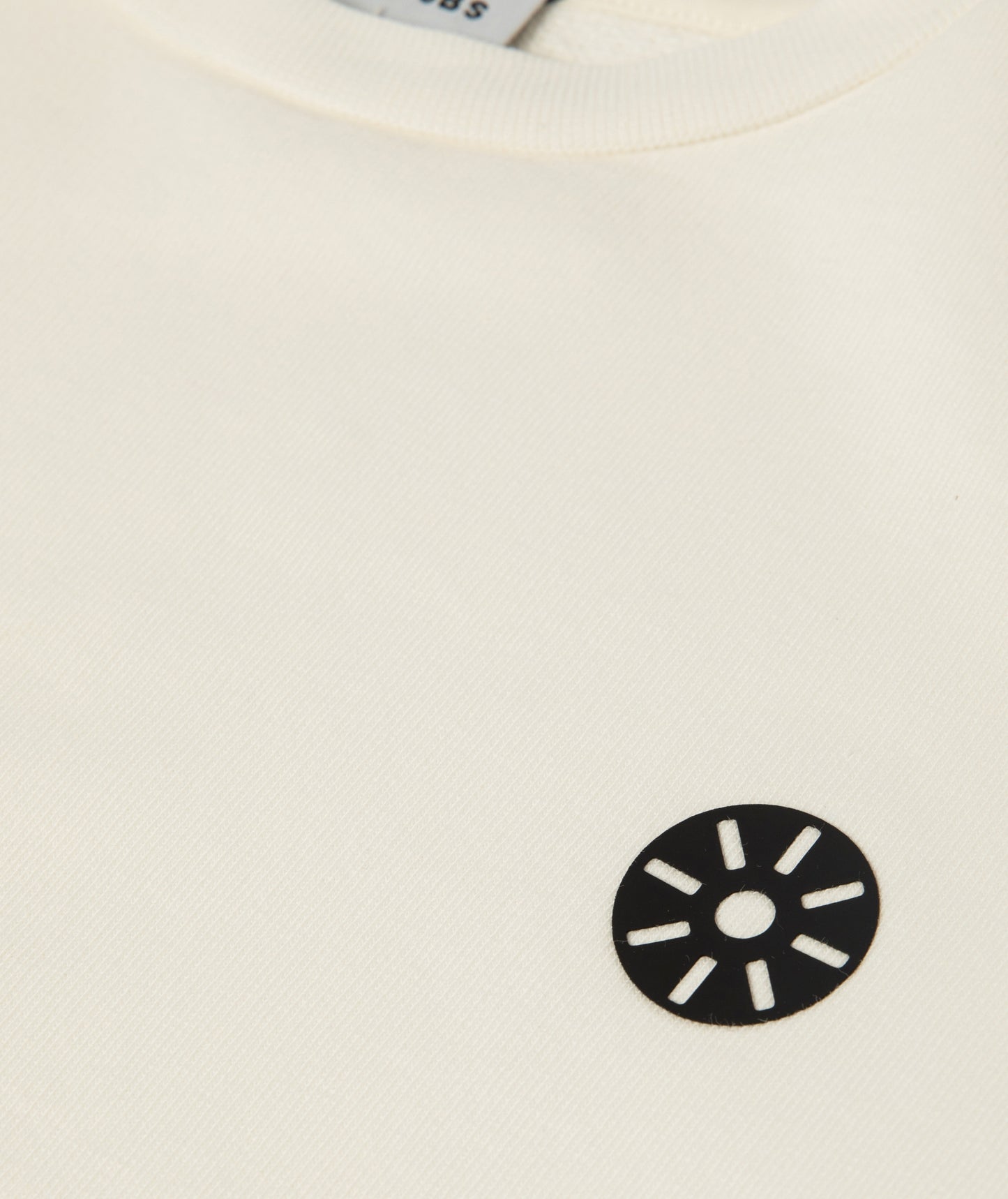Close-up of Goldencubs white cotton girls sweatshirt featuring soft ribbed collar and black circular logo patch — premium kids athleisurewear fabric detail.