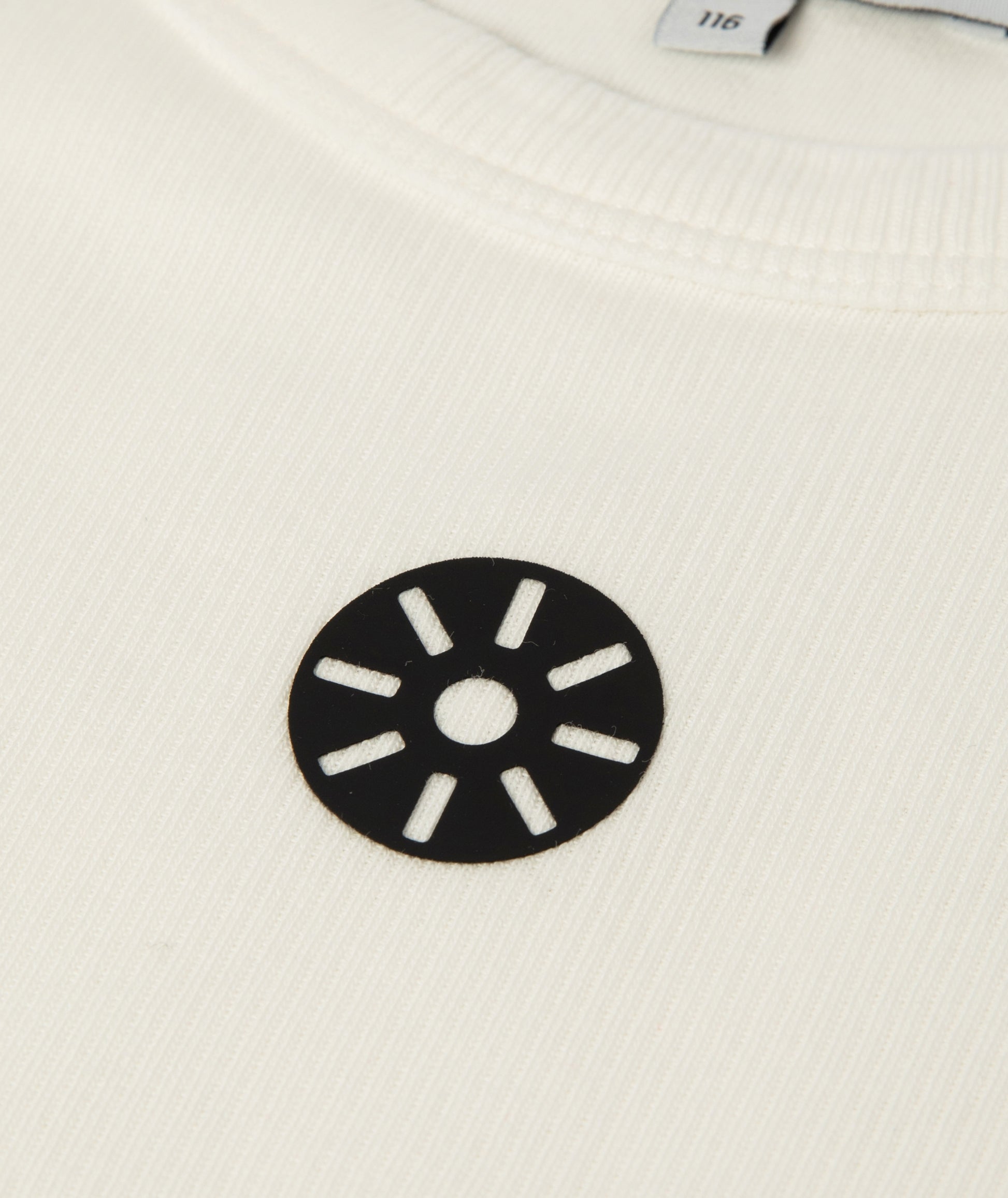 Close-up of Goldencubs white ribbed cotton girls tank top showing fabric texture and circular black logo patch detail.