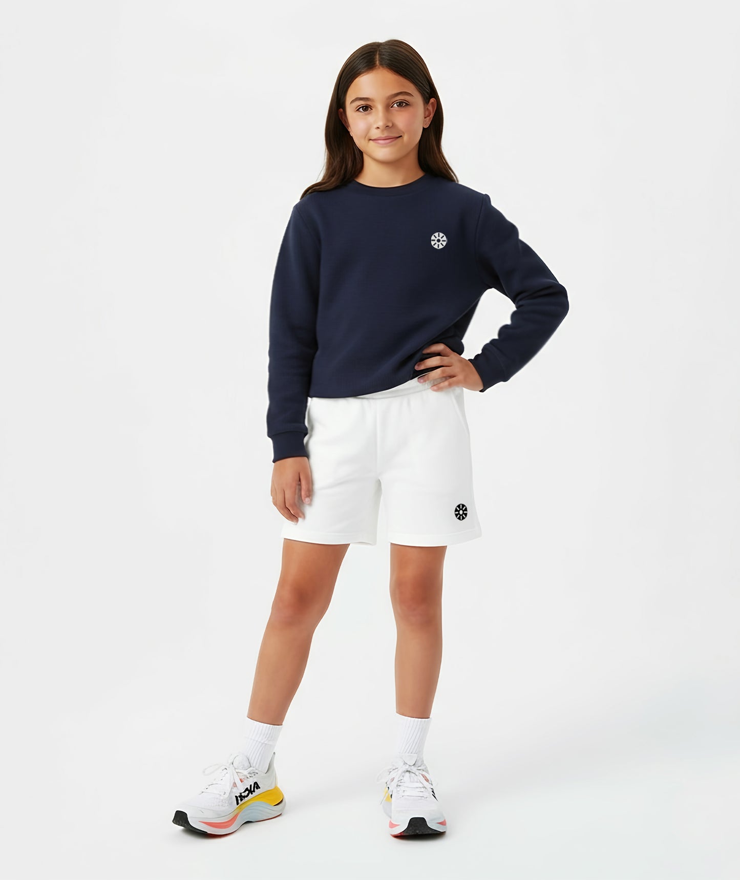 A girl wearing white cotton shorts paired with a navy sweatshirt and colorful sneakers, styled in a modern Goldencubs athleisure outfit perfect for everyday comfort and play.