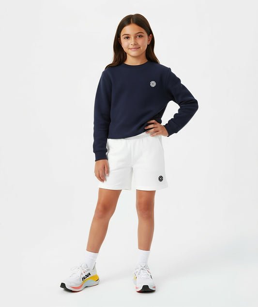 A girl wearing white cotton shorts paired with a navy sweatshirt and colorful sneakers, styled in a modern Goldencubs athleisure outfit perfect for everyday comfort and play.
