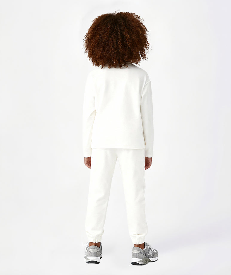 Rear view of a girl in white cotton sweatpants and a long-sleeve top, showing the soft elastic waistband and comfortable relaxed fit of this Goldencubs outfit.